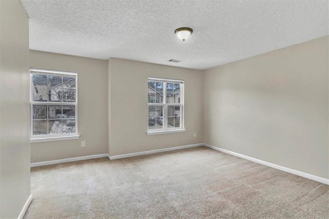 carpeted empty room with a textured ceiling