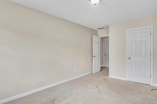 unfurnished bedroom featuring light colored carpet and a textured ceiling