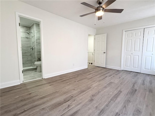 unfurnished bedroom featuring baseboards, wood finished floors, connected bathroom, and a closet