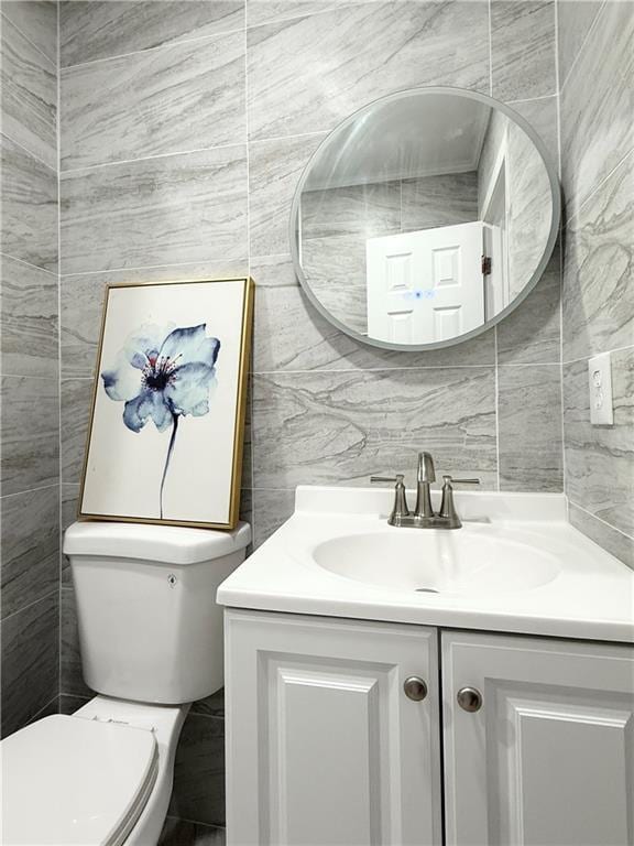 half bath featuring toilet, tile walls, and vanity