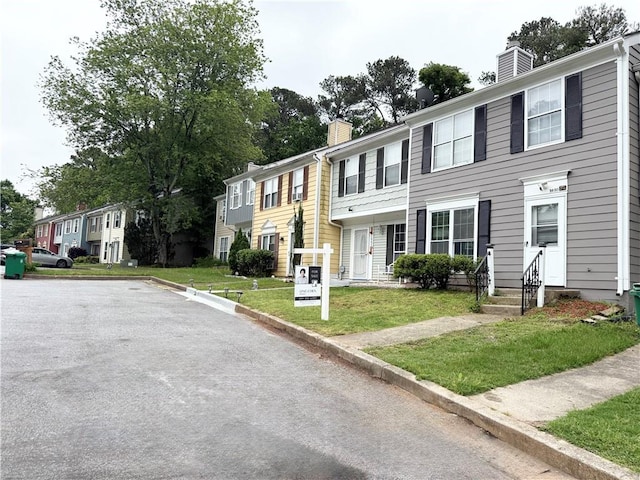 view of property featuring a chimney, a residential view, and a front yard