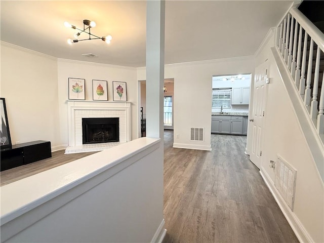 hall featuring dark wood finished floors, visible vents, ornamental molding, and stairway