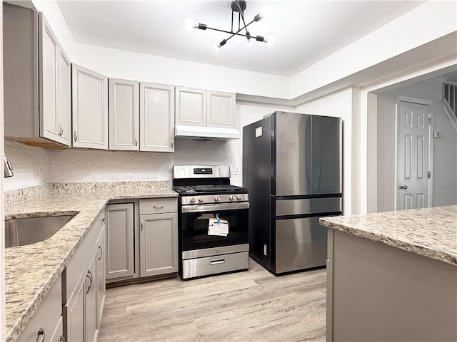 kitchen with light stone counters, light wood-style flooring, stainless steel appliances, and under cabinet range hood