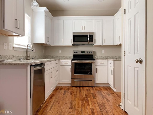 kitchen featuring white cabinetry, sink, stainless steel appliances, and light wood-type flooring