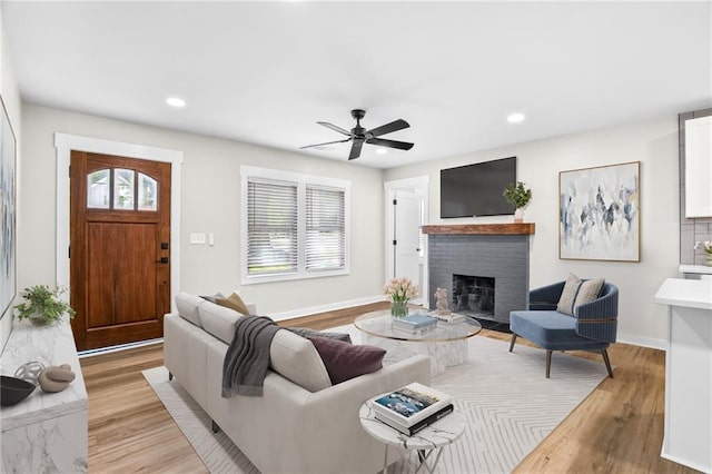 living room with a fireplace, light hardwood / wood-style floors, and ceiling fan