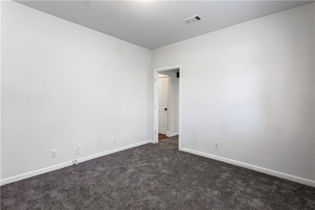 unfurnished room with dark colored carpet, visible vents, and baseboards