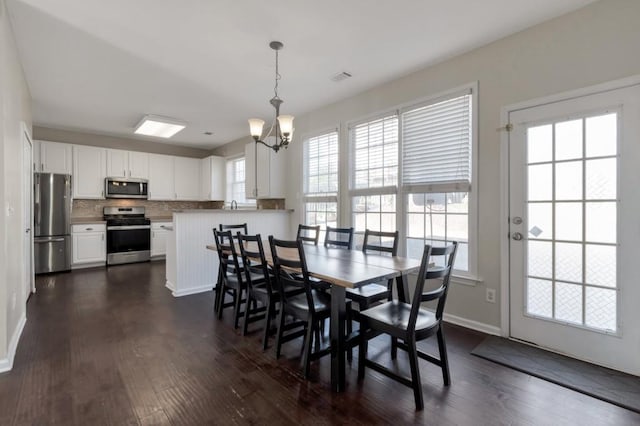 dining room with dark hardwood / wood-style floors and an inviting chandelier