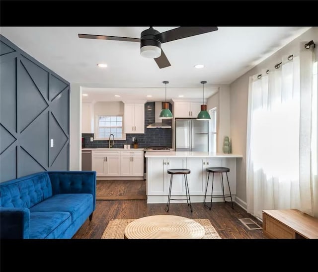 kitchen with sink, a kitchen breakfast bar, white cabinetry, stainless steel fridge, and decorative light fixtures