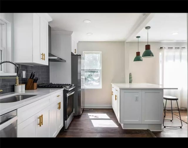 kitchen featuring white cabinets, dark hardwood / wood-style flooring, appliances with stainless steel finishes, pendant lighting, and sink