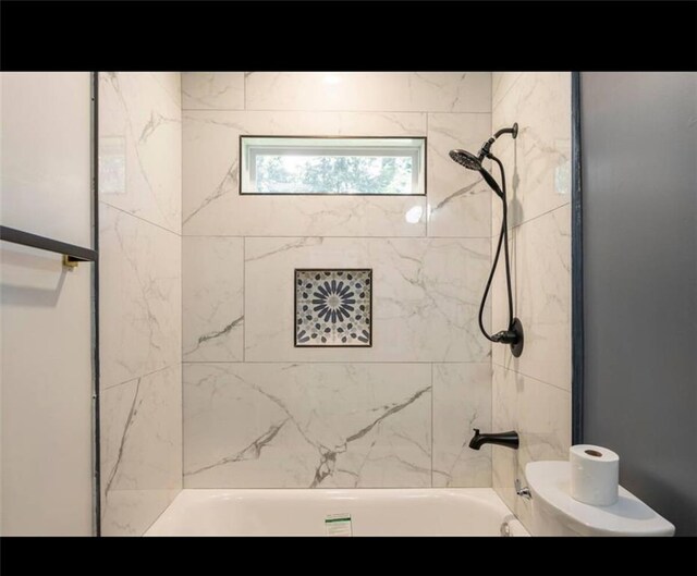 bathroom featuring tiled shower / bath combo and toilet