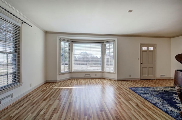 unfurnished living room featuring baseboards, wood finished floors, and crown molding