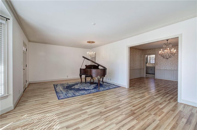 living area with light wood finished floors, wallpapered walls, ornamental molding, wainscoting, and an inviting chandelier