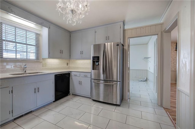 kitchen featuring a sink, black dishwasher, stainless steel fridge, light countertops, and a chandelier