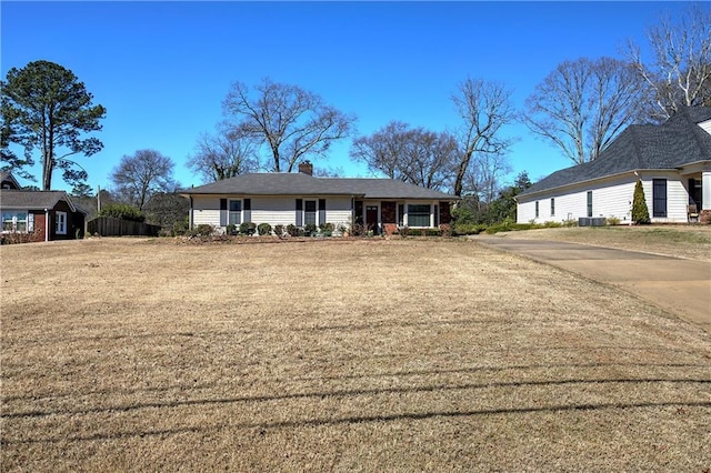 view of front of home with central AC unit, a chimney, and a front yard