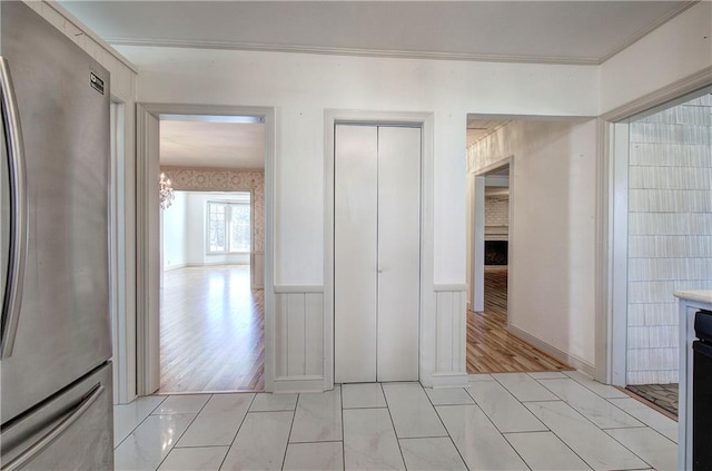 hallway featuring light wood-style flooring and a wainscoted wall