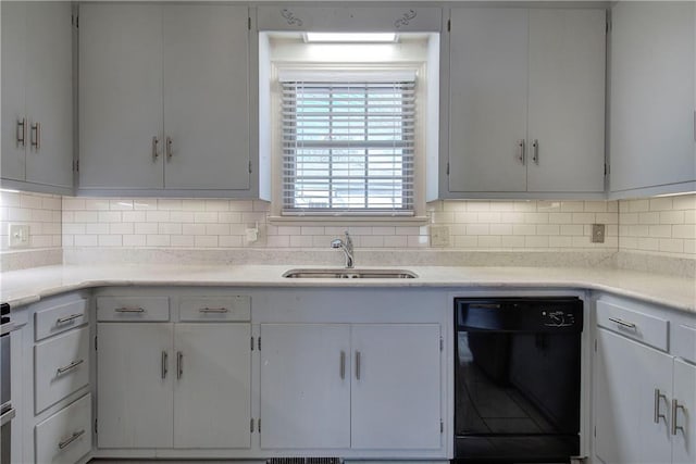 kitchen with dishwasher, light countertops, decorative backsplash, and a sink