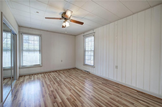 spare room featuring visible vents, light wood-style flooring, baseboards, and a ceiling fan