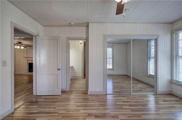 unfurnished bedroom featuring a closet, a fireplace, light wood-type flooring, and baseboards