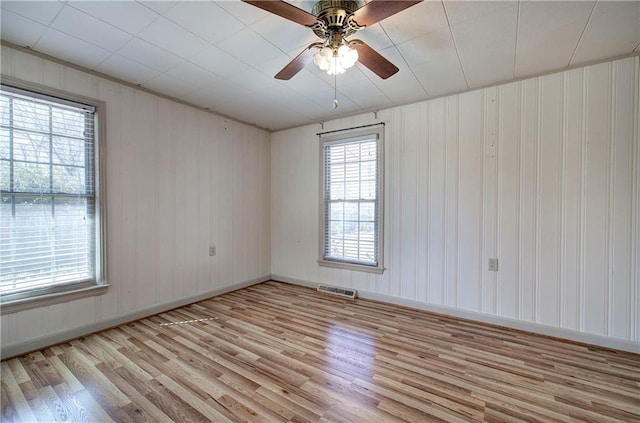 empty room featuring visible vents, baseboards, ceiling fan, and wood finished floors