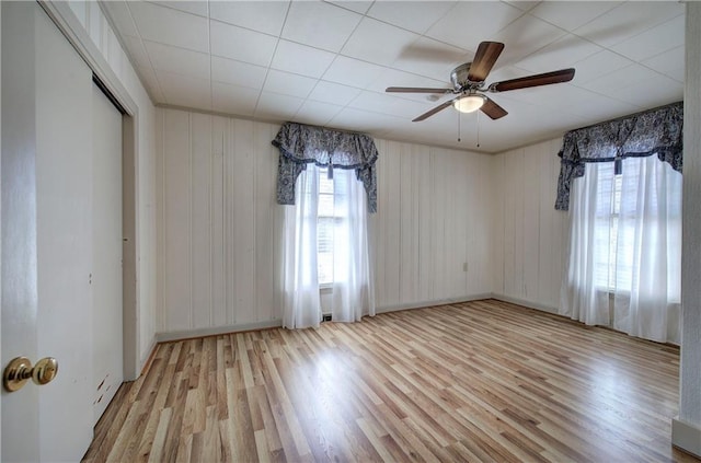 empty room with a healthy amount of sunlight, baseboards, ceiling fan, and wood finished floors