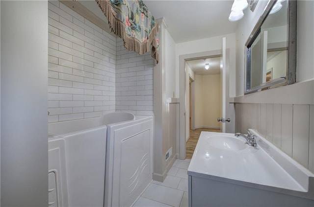 bathroom featuring tile patterned floors, visible vents, a washtub, wainscoting, and vanity