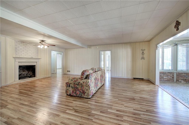 living room featuring visible vents, a ceiling fan, a fireplace, and light wood finished floors