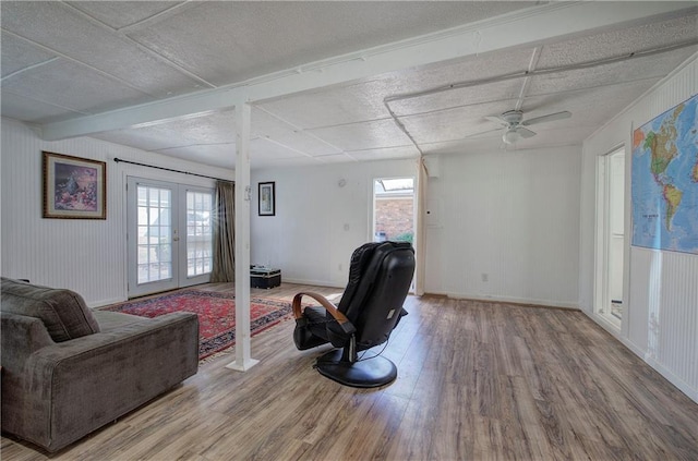 living room featuring ceiling fan, french doors, baseboards, and wood finished floors