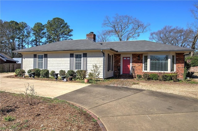 ranch-style house featuring brick siding, a chimney, and fence