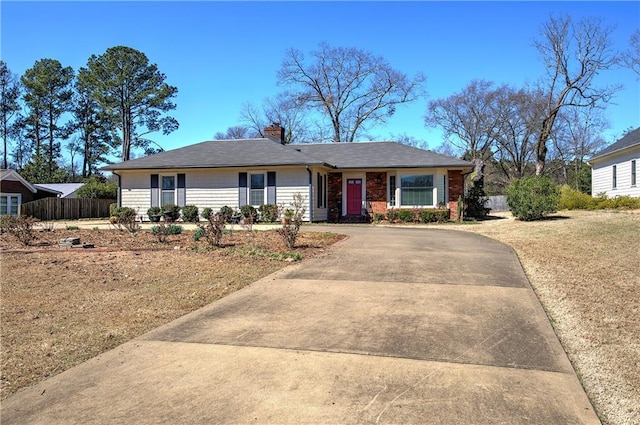 ranch-style house featuring fence, driveway, and a chimney