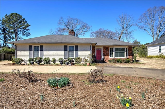 ranch-style house featuring a chimney and fence