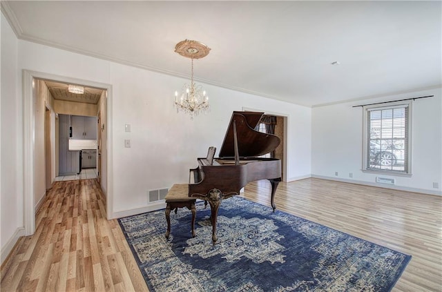 living area with a notable chandelier, visible vents, light wood-type flooring, and baseboards