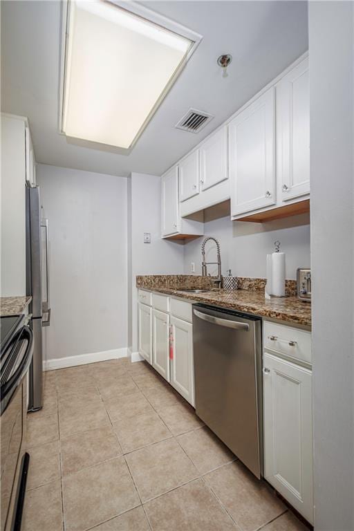 kitchen with light tile patterned flooring, stainless steel appliances, white cabinets, and sink