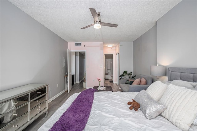 bedroom with ceiling fan, dark wood-type flooring, and a textured ceiling