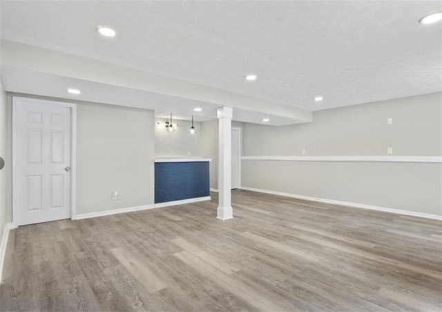 finished below grade area with recessed lighting, baseboards, and wood finished floors