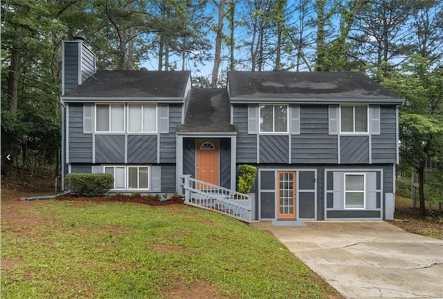 bi-level home with a chimney, concrete driveway, and a front yard