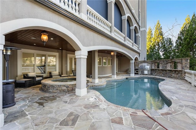 view of pool with an in ground hot tub, an outdoor living space, a patio, and exterior kitchen