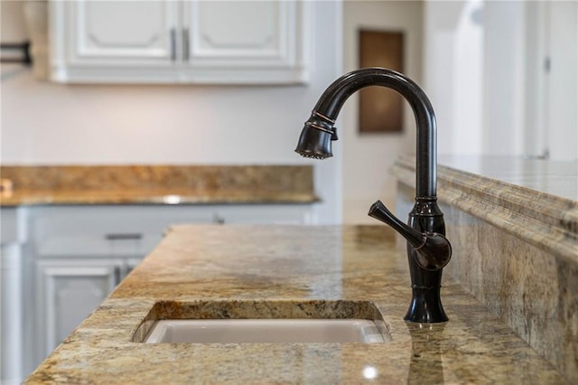 details featuring white cabinetry, sink, and light stone counters