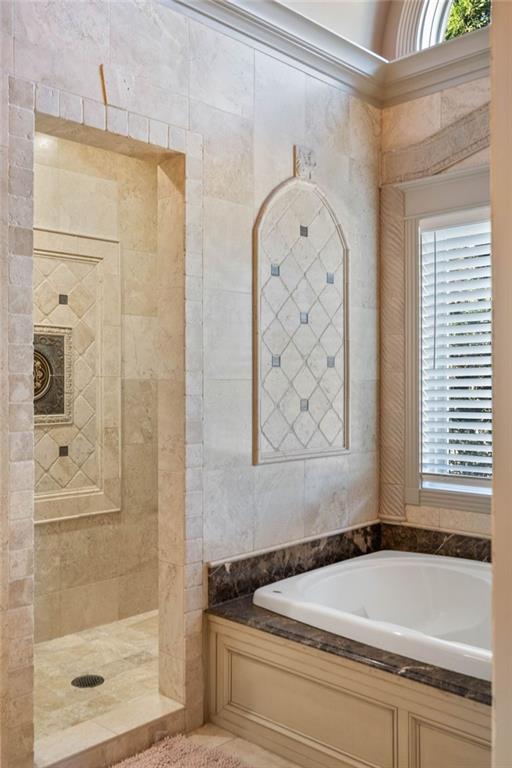 bathroom featuring ornamental molding, plenty of natural light, and independent shower and bath