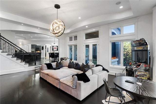 living room with a chandelier, a raised ceiling, and french doors