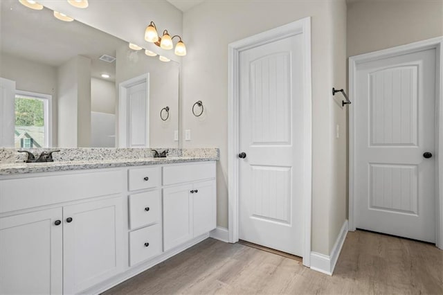 full bathroom featuring wood finished floors, double vanity, and baseboards