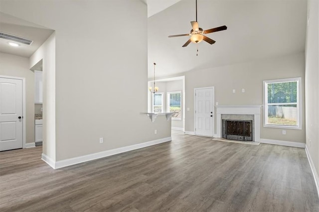 unfurnished living room with ceiling fan with notable chandelier, wood finished floors, baseboards, and visible vents