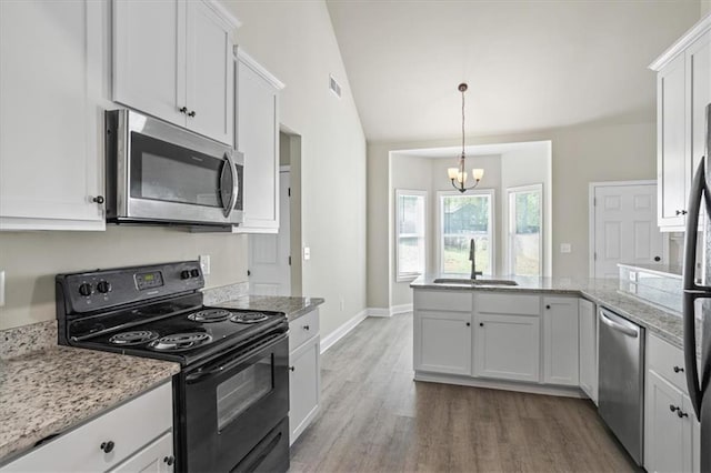 kitchen with an inviting chandelier, a peninsula, white cabinetry, appliances with stainless steel finishes, and a sink
