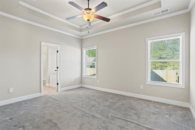 carpeted empty room with visible vents, baseboards, a raised ceiling, ornamental molding, and ceiling fan