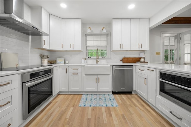 1104 Warrenhall Ln NE, Brookhaven, GA 30319 - kitchen with wall chimney range hood, stainless steel appliances, light wood-style flooring, light countertops, and recessed lighting