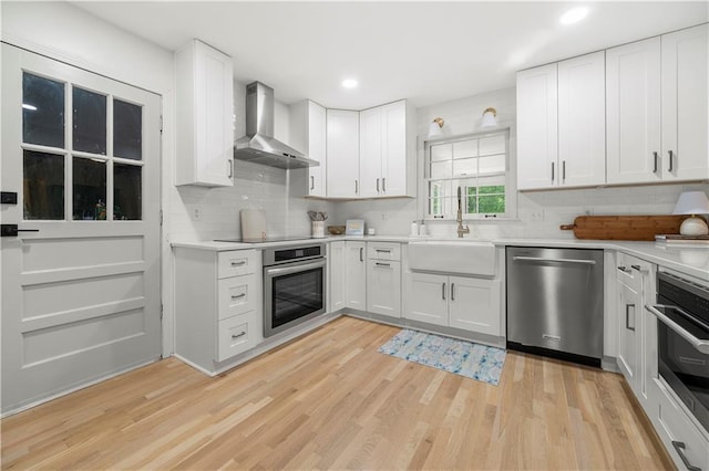 1104 Warrenhall Ln NE, Brookhaven, GA 30319 - kitchen featuring stainless steel appliances, wall chimney range hood, light wood-style flooring, light countertops, and decorative backsplash