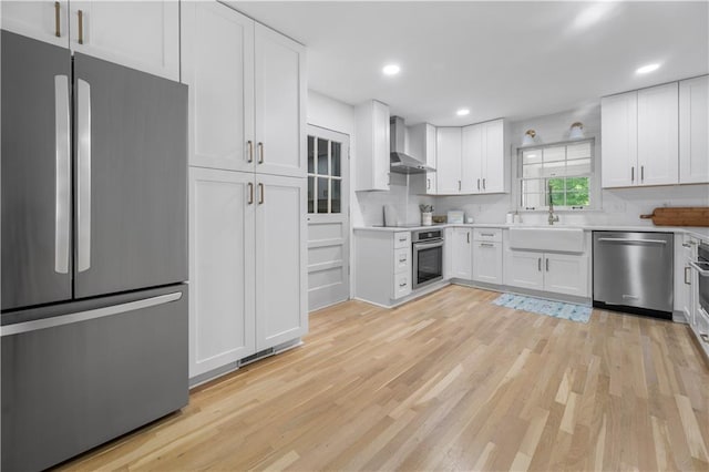 1104 Warrenhall Ln NE, Brookhaven, GA 30319 - kitchen featuring stainless steel appliances, wall chimney range hood, white cabinets, light wood-style floors, and recessed lighting