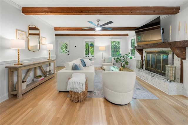 1104 Warrenhall Ln NE, Brookhaven, GA 30319 - living room featuring beamed ceiling, light wood-style flooring, a glass covered fireplace, a ceiling fan, and crown molding