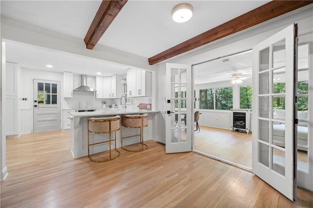 1104 Warrenhall Ln NE, Brookhaven, GA 30319 - kitchen with french doors, wall chimney exhaust hood, beamed ceiling, white cabinets, and a breakfast bar area