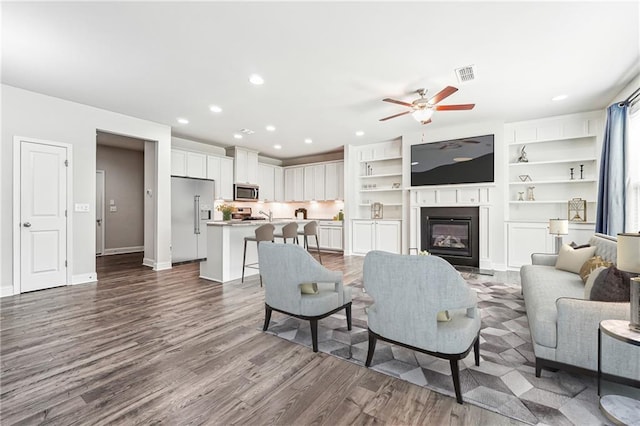 791 Belrose Dr, Smyrna, GA 30080 - living room featuring recessed lighting, dark wood-style floors, ceiling fan, a glass covered fireplace, and baseboards