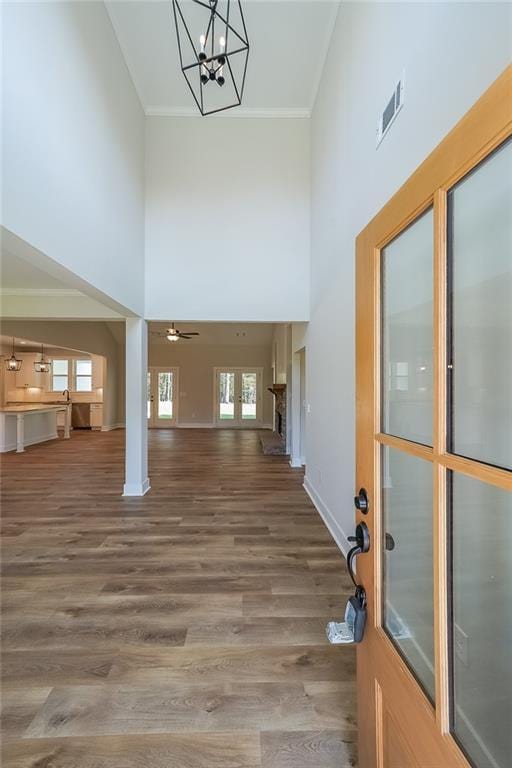 entryway featuring ornamental molding, visible vents, a high ceiling, and wood finished floors